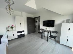 a white living room with a table and chairs at Apartamenty Emerald Hills in Januszowa