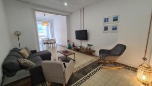 Una sala de estar con un sofá y sillas y un televisor. en Casa Portela, en Cartagena