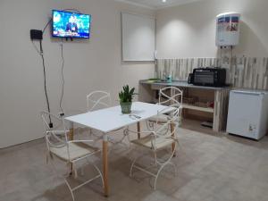 una mesa blanca y sillas en una habitación con TV en El Solar Departamentos Tartagal en Tartagal