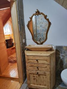baño con lavabo y tocador de madera con espejo. en Brvnara Ibar, en Rožaje