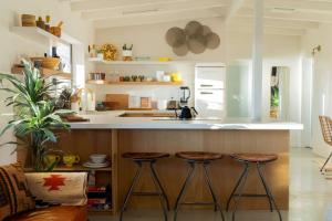 a kitchen with three bar stools and a counter at Peaceful Desert Paradise - Casa Coyote in Joshua Tree