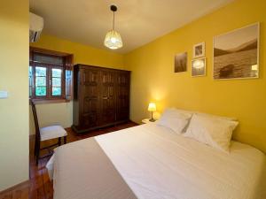 a bedroom with a white bed and a yellow wall at São Jorge Country House in Penafiel