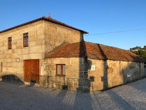 an old stone building with a brown door and a cobblestone street at São Jorge Country House in Penafiel
