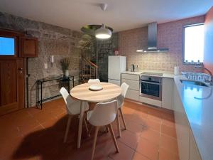 a kitchen with a wooden table and white chairs at São Jorge Country House in Penafiel