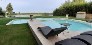 サン・ジルにあるMas du Versadou, dans un espace naturel protégé, piscine Chauffée, Spa et salle de jeuxの庭園内のスイミングプール(椅子、テーブル付)
