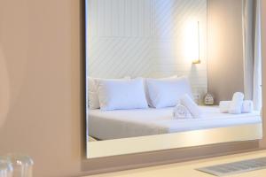 a bedroom with a bed with white pillows and a mirror at BlueBlood - The Rooms in Kalamata