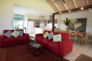 a living room with two red couches and a table at 2/24 Donkin - Luxury - Absolute Beachfront in Mission Beach