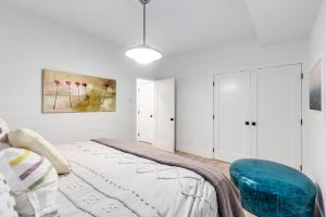 a white bedroom with a bed and a blue chair at Crescent Beach is a walk away from Casa Altamira! in Surrey