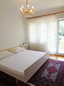 een slaapkamer met een groot wit bed en een kroonluchter bij Apartment Moscenicka Draga 2327c in Mošćenička Draga