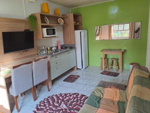 a living room with a kitchen with green walls at Fazendinha Adoro in Farroupilha