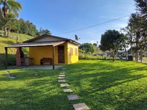 a small yellow house in the middle of a yard at Fazendinha Adoro in Farroupilha