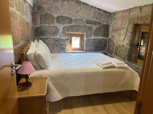 een slaapkamer met een bed in een stenen muur bij Casa da Lage - Lindas vistas - Gerês - Rio - Campo in Geres