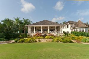 a large white house with a green lawn at Sunny Vacation Villa No 5 in Montego Bay