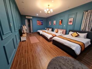 2 Betten in einem Zimmer mit blauen Wänden und Holzböden in der Unterkunft Bich Ngoan HOTEL in Trà Vinh