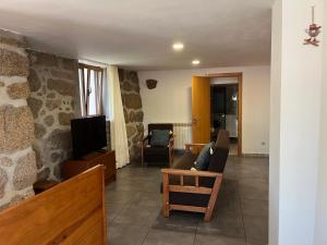 uma sala de estar com um sofá e uma televisão em Casa da Lage - Piscina privada - Vistas rio no Gerês