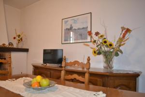 a room with a table with a vase of fruit and a television at Appartamento La Chiusa in Monticiano
