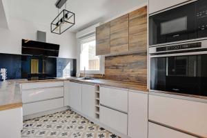 a kitchen with white cabinets and black appliances at Cosy apartment & balcony -1BR 4P- Levallois-Perret in Levallois-Perret