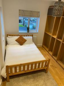 a small bedroom with a bed with a window at Large, light & airy 4 bedroom home on quiet road in London