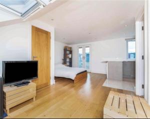 a large living room with a television and a bed at Large, light & airy 4 bedroom home on quiet road in London