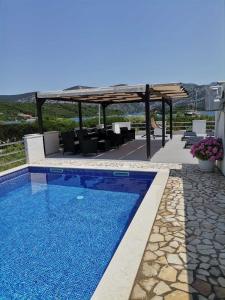 a swimming pool with a gazebo and chairs at Family friendly apartments with a swimming pool Kneza, Korcula - 9130 in Račišće