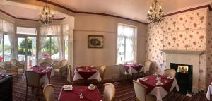 uma sala de jantar com mesas e cadeiras e uma lareira em Devonia Express em Eastbourne