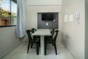 a small dining room with a white table and black chairs at Flórida Premium in Bombinhas