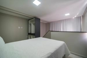 1 dormitorio con cama blanca y espejo en Flórida Premium, en Bombinhas