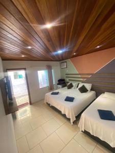 1 dormitorio con 2 camas y techo de madera en Sunrise Suítes, en Arraial do Cabo