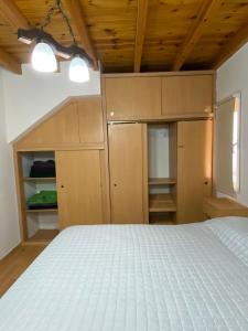 Schlafzimmer mit einem weißen Bett und Holzdecken in der Unterkunft La alegre! Hermosa casa centrica y cerca del mar in Puerto Madryn