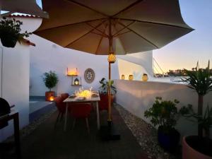 a table with an umbrella in a room with plants at Casa Pirilampo Ferragudo in Ferragudo