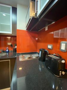 eine Küche mit orangefarbenen Wänden und einer schwarzen Arbeitsplatte in der Unterkunft Andino Apartaments Rental Capital in San Juan