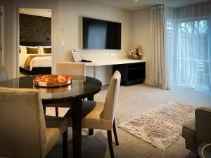 a living room with a dining room table and a bedroom at The Sails Nelson in Nelson
