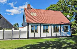 una casa con techo rojo y valla blanca en Beautiful Home In Aakirkeby With Kitchen, en Spidsegård