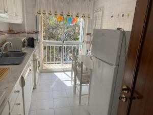 a kitchen with a refrigerator and a table and a window at Painel da Caparica in Costa da Caparica