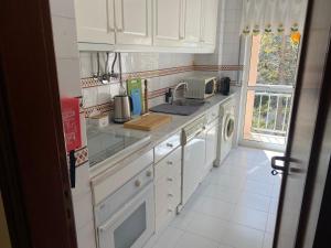 a white kitchen with a sink and a dishwasher at Painel da Caparica in Costa da Caparica