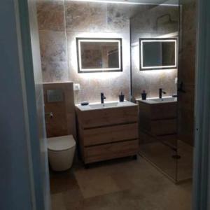 a bathroom with two sinks and a toilet and two mirrors at Le Studio d Aurélie avec SPA été en pleine campagne et proche de toute commodité in Roquemaure