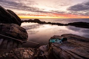 une masse d'eau avec un bateau au milieu des rochers dans l'établissement Reflections Bermagui - Holiday Park, à Bermagui