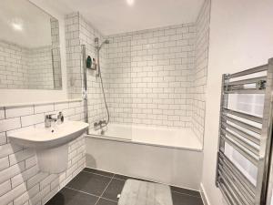 a white bathroom with a sink and a bath tub at Morden 2 Bed Apartment - Manchester Old Trafford in Manchester