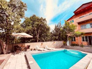 a swimming pool with chairs and a table and an umbrella at Awesome Large 3 Floor Villa Dilijan , 8 Bedrooms+4.5 Bathrooms+Swimming Pool, Nice Mountain View in Dilijan
