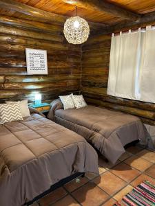 um quarto com 2 camas num chalé de madeira em Sommerwind Cabañas em La Estancia