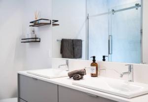 a white bathroom with two sinks and a mirror at Revy Bliss - Dazzling Condo in the Mountains in Revelstoke +17 photos