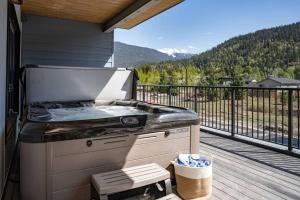 a grill on a deck with a view of the mountains at Revy Bliss - Dazzling Condo in the Mountains in Revelstoke