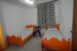 a bedroom with two beds and a chair in it at Orikum Veranda Apartments in Orikum