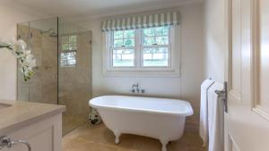 a white bathroom with a tub and a shower at Somerleyton Cottage in Wildes Meadow