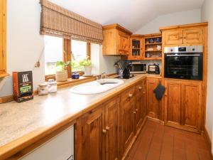 een keuken met houten kasten en een wastafel bij Green Farm Cottage in Ashbourne