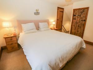 a bedroom with a large white bed and a wooden door at Green Farm Cottage in Ashbourne