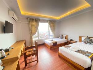 Cette chambre comprend deux lits, un bureau et une fenêtre. dans l'établissement LOI LOUNG HOTEL, à Taunggyi