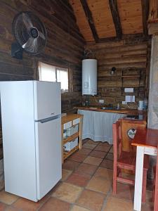 uma cozinha com um frigorífico branco e uma mesa em Sommerwind Cabañas em La Estancia