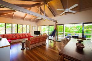 ein Wohnzimmer mit einem Sofa, einem Tisch und Stühlen in der Unterkunft Breeya - A great tropical escape. Sleeps 9 in Mission Beach