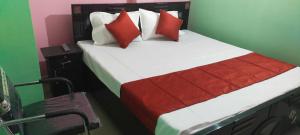 um quarto com uma cama com almofadas vermelhas e brancas em SPOT ON Hotel Royal Garden em Dānāpur